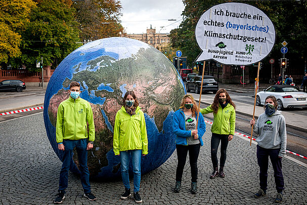 Personen vor Erdkugel Klimaaktion